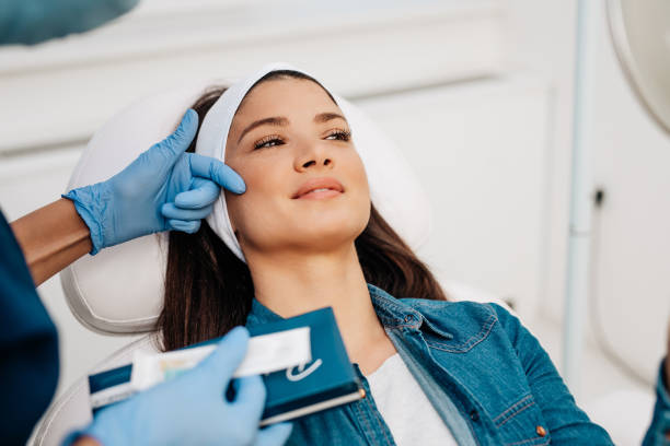 Woman sitting in a chair, about to receive dermal fillers from professional personnel.
